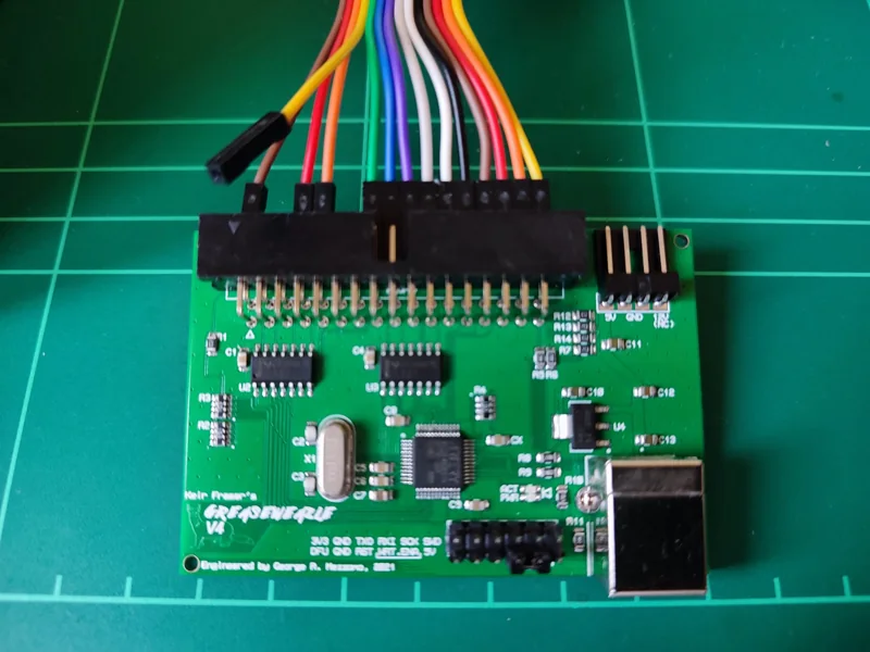 Greaseweazle floppy-imaging board connected to jumper wires on a cutting mat